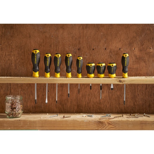 Photo of STANLEY STHT16147-0 screwdriver set, eight black and yellow screwdrivers with ergonomic handles on a workshop shelf.