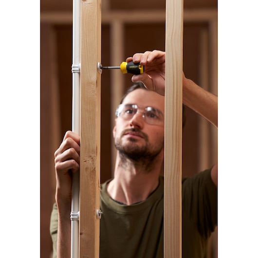 Photo of STANLEY STHT16154-0 screwdriver in use on wooden framing, close-up action shot.