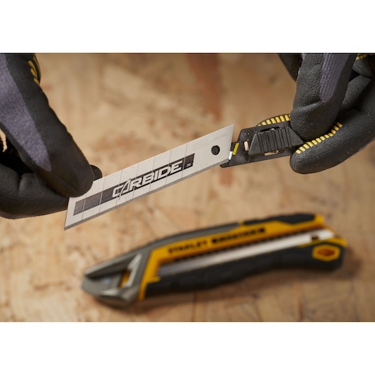Photo of STANLEY STHT2-11818 utility knife blade being loaded, with black and yellow handle visible.