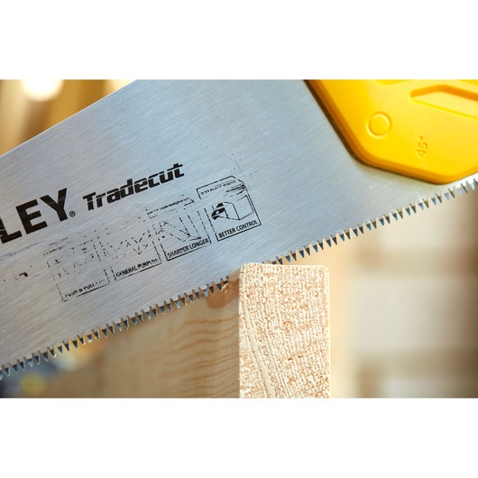 STANLEY STHT20348-1 hand saw with sharp teeth cutting wood, close-up angle on blade and handle.