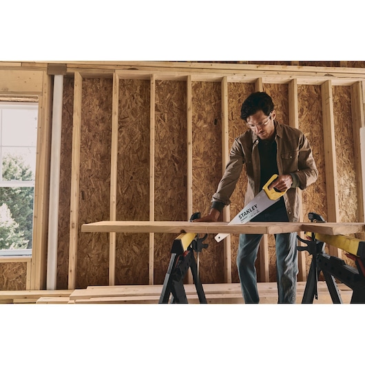 STANLEY STHT20350 hand saw in use cutting wood, photo of product in construction setting.