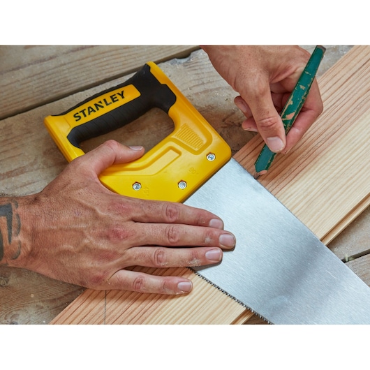 Photo of STANLEY STHT20370-1 hand saw with yellow handle used on wooden planks, top view.
