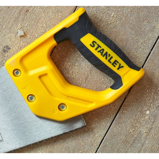 STANLEY STHT20370-1 yellow and black hand saw handle on wooden surface, close-up angle.