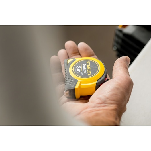 Photo of STANLEY STHT36802-0 yellow and black DualLock tape measure held in hand, 3m length visible.