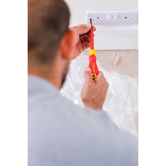 Photo of a person using a STANLEY STHT60032-0 red and yellow screwdriver to install a wall power socket.