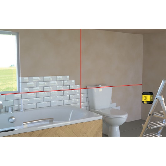STANLEY STHT77498-1 laser level projecting red lines in a bathroom with bath, toilet, and ladder, front angle.