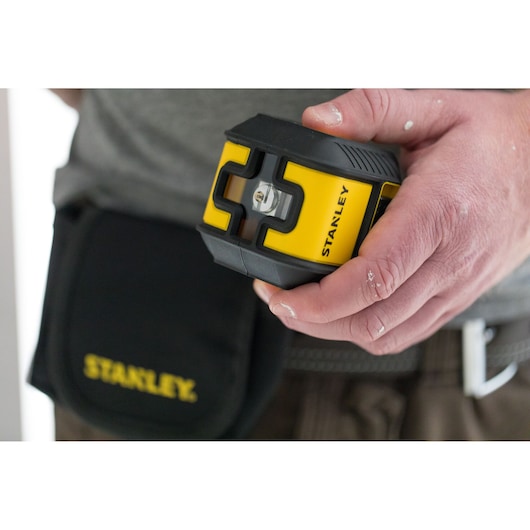 Photo of STANLEY STHT77499-1 laser level tool with black and yellow casing held in hand, tool pouch visible.