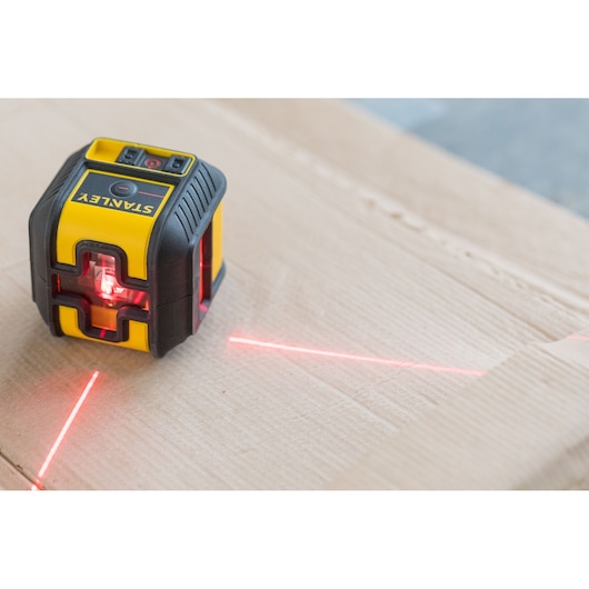 Photo of STANLEY STHT77502-1 laser level projecting red lines on a cardboard surface.