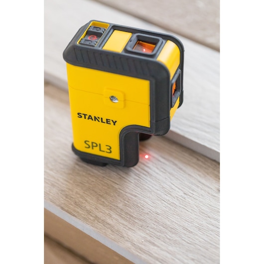 STANLEY STHT77503-1 laser level SPL3, yellow and black, projecting red laser dot, close-up angle.