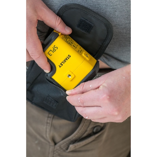 Photo of STANLEY STHT77503-1 yellow laser level being placed in black pouch, close-up view.