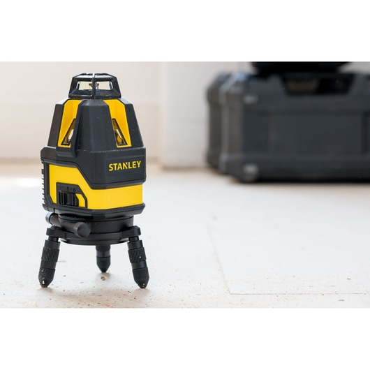 STANLEY STHT77524-1 laser level on tripod, yellow and black, indoor setting, product photography.