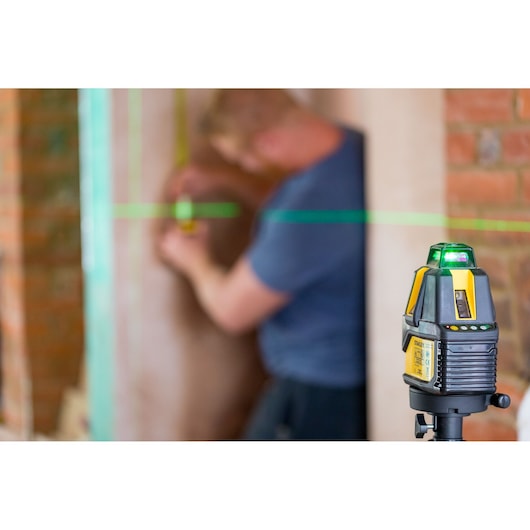 STANLEY STHT77524-1 laser level projecting green line in construction setting, close-up side angle.