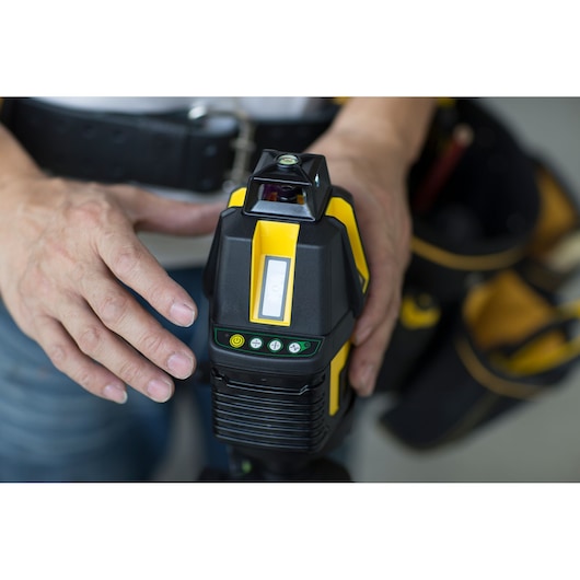 STANLEY STHT77524-1 laser level device held by a person, close-up of controls and yellow-black design.