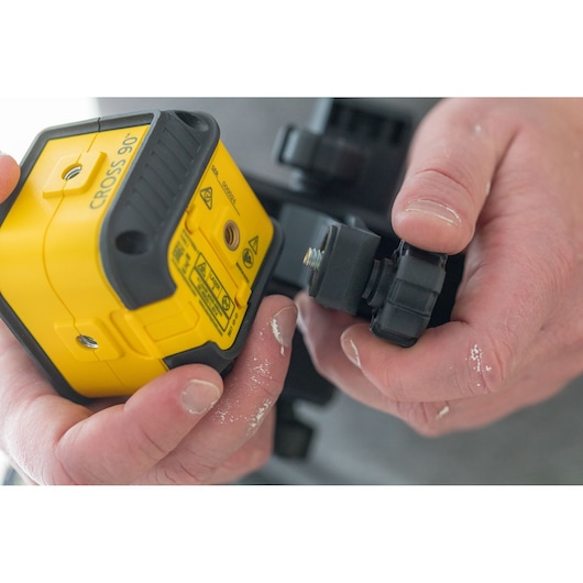 STANLEY STHT77592-1 yellow cross line laser level being attached to mounting bracket, close-up.