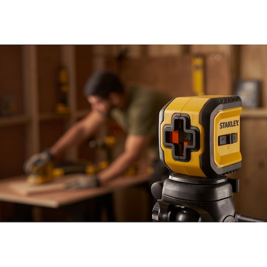 STANLEY STHT77611-0 yellow and black laser level mounted on tripod in workshop photography.