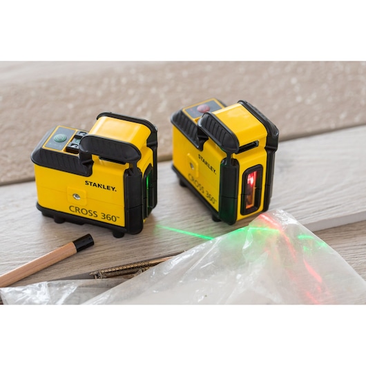 STANLEY STHT77640-1 yellow CROSS 360 laser level tools on wood surface, laser lines visible, photography angle.