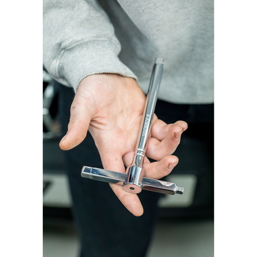 STANLEY STHT80872-0 T-handle tap wrench held in hand, chrome finish, photography close-up.