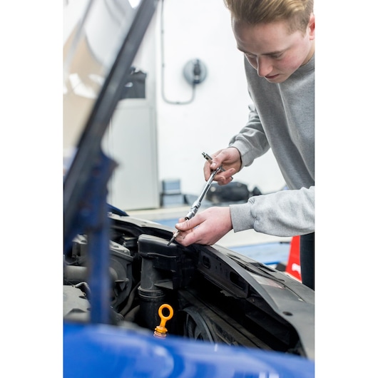 STANLEY STHT80872-0 photography showing a person using a ratchet wrench on a car engine in a garage.