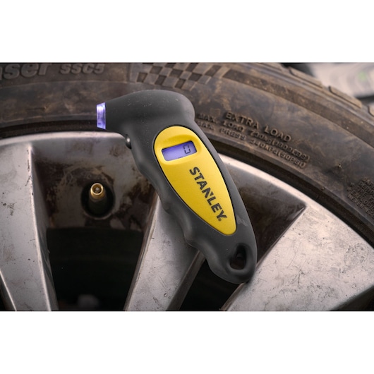 STANLEY STHT80874-0 digital tire pressure gauge close-up on a car wheel.
