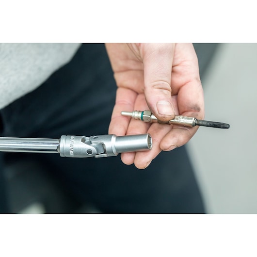 STANLEY STHT80888-0 photography of a hand holding a spark plug and a socket wrench tool close-up.