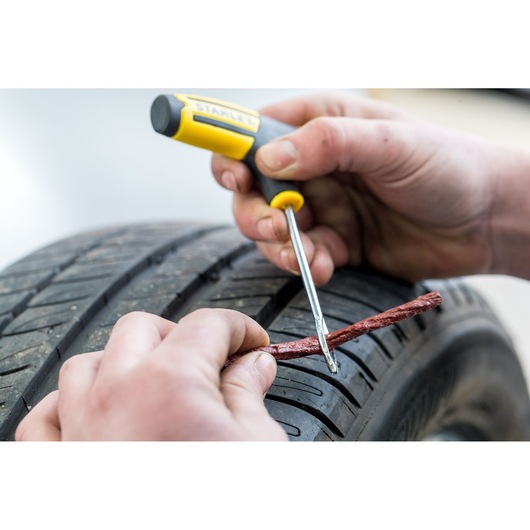 STANLEY STHT80891-0 tire repair tool used to insert plug in car tire, close-up photo.