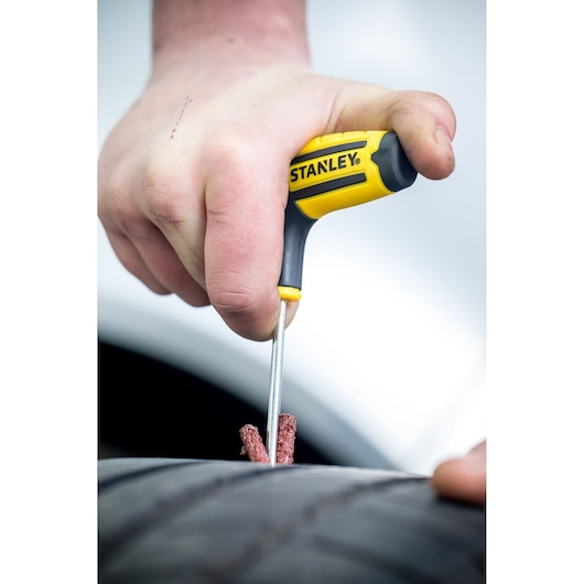 Stanley STHT80891-0 T-handle tire repair tool in use on a car tire, close-up photography.