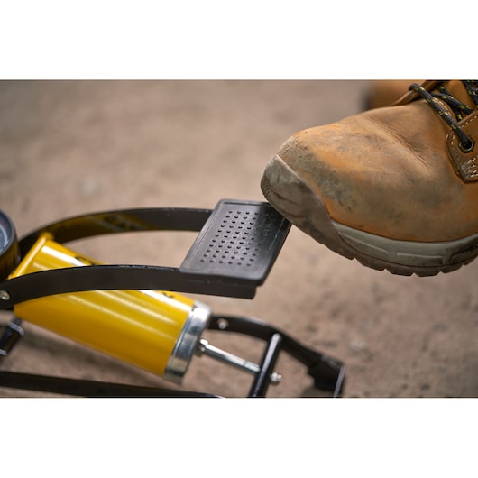 STANLEY STHT80894-1 foot pump with boot pressing pedal, shown close-up outdoors.