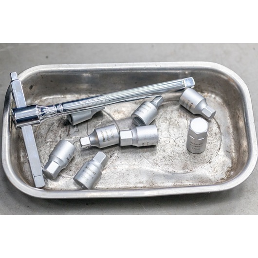 STANLEY STHT81575-0 socket wrench and seven silver sockets in a metal tray, product photography from above.