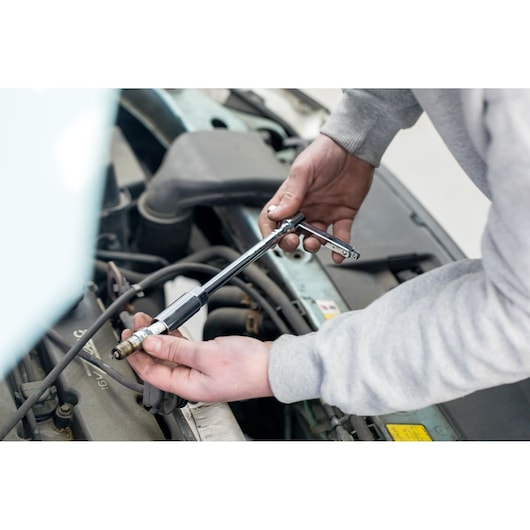 STANLEY STHT81582-0 ratchet wrench in use for spark plug removal, automotive photography.