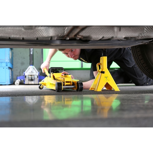 STANLEY STMT81255-1 yellow jack stand and floor jack under car, side angle, automotive tool application.