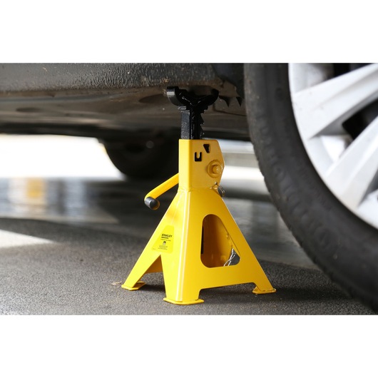 STANLEY STMT81255-1 yellow steel jack stand under car near wheel, side angle.