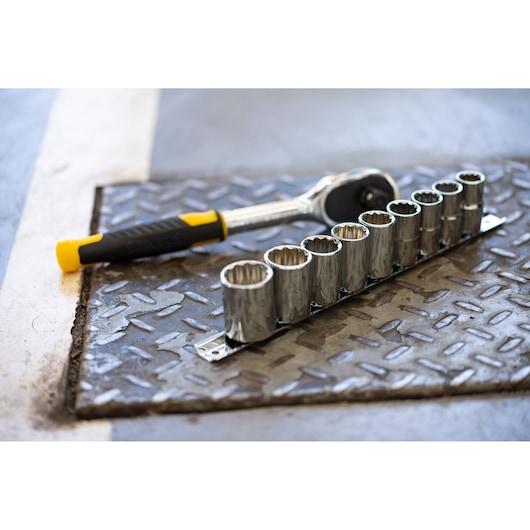 STANLEY STMT82666-0 socket wrench and nine-piece socket set on metal floor, angled view.