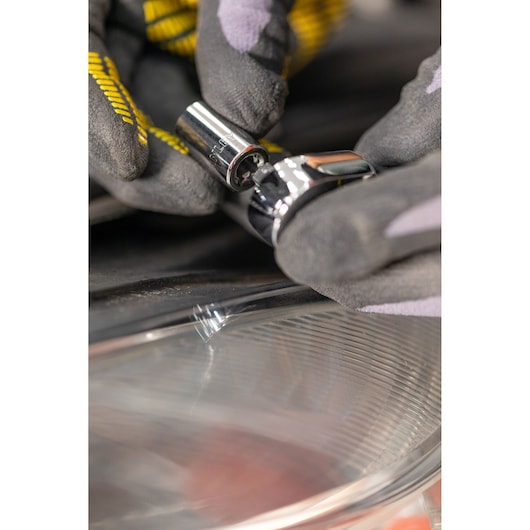 STANLEY STMT82666-0 socket held by gloved hand near car headlight, close-up photo.