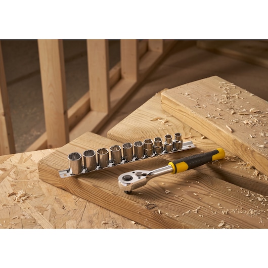 STANLEY STMT82670-0 11-piece ratchet and socket set with yellow and black handle on wooden surface.
