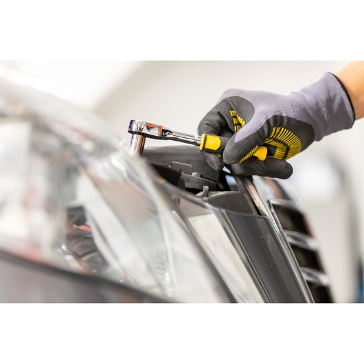 STANLEY STMT82672-0 ratchet set used on car headlight, close-up, showing tool grip and yellow details.