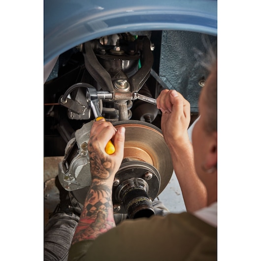 STANLEY STMT82672-0 ratchet and socket set in use on car brake assembly, seen from side angle.