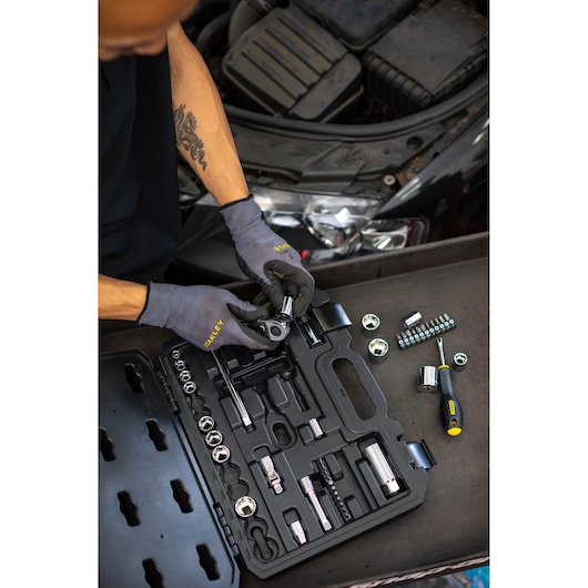 STANLEY STMT82828-1 socket set in black case, mechanic using tools near car engine, photography from above.
