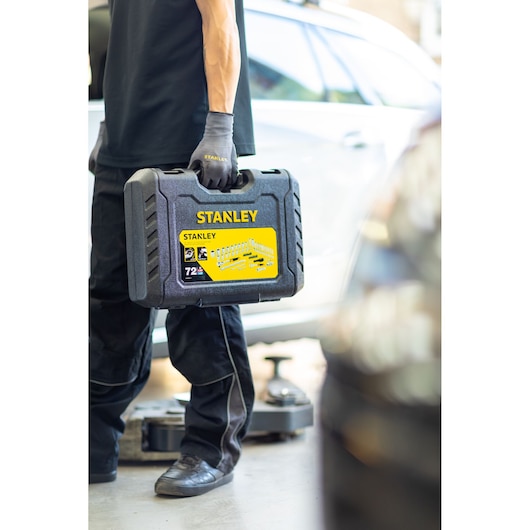 STANLEY STMT82828-1 socket set case held by person in gloves, shown in a garage setting.