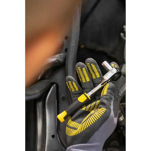 STANLEY STMT82828-1 ratchet wrench with black and yellow handle, held in gloved hand, close-up.