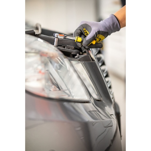 STANLEY STMT82828-1 ratchet screwdriver used to tighten bolt on car headlight, close-up.