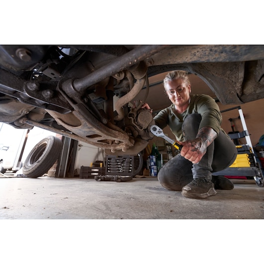 Photo of STANLEY STMT82832-1 ratchet wrench used for automotive repair under a vehicle in a garage setting.