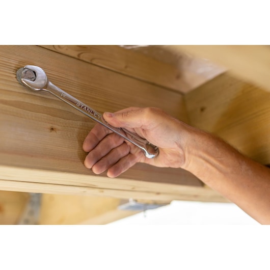 Photo of STANLEY STMT82842-0 wrench tightening bolt on wood, close-up hand holding tool.
