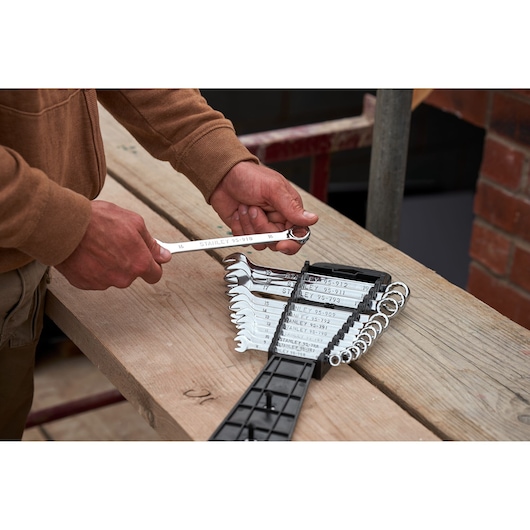 STANLEY STMT82843-0 combination wrench set, 12 pieces, shown on a wooden workbench, person holding one wrench.
