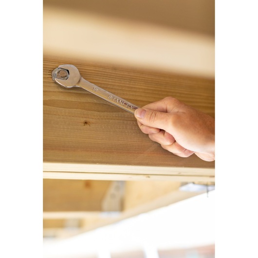 Photo of STANLEY STMT89912-0 wrench being used on a bolt on wooden beam, side angle.