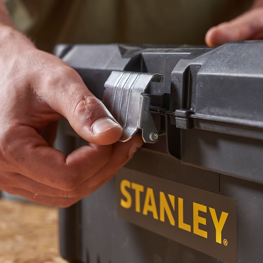 STANLEY STST1-75518-KR toolbox close-up, hand opening metal latch, black case, yellow logo.