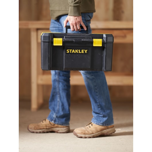 STANLEY STST1-75520 black and yellow toolbox being carried, product photography in workshop setting.