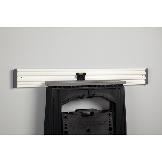 STANLEY STST82608-1 wall-mounted rail with black folding sawhorse hung, front angle, workshop storage accessory.