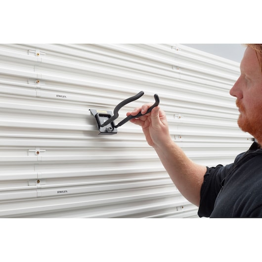 STANLEY STST82609-1 wall-mounted storage hook being installed on white slatwall panel.