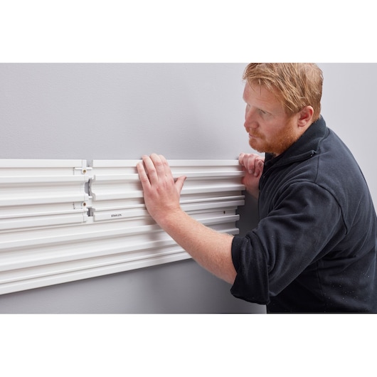 STANLEY STST82610-1 wall panel installation, close-up of hands attaching white mounting panels.