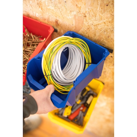 STANLEY STST82740-1 blue storage bin with coiled cable, viewed from above in workshop setting.